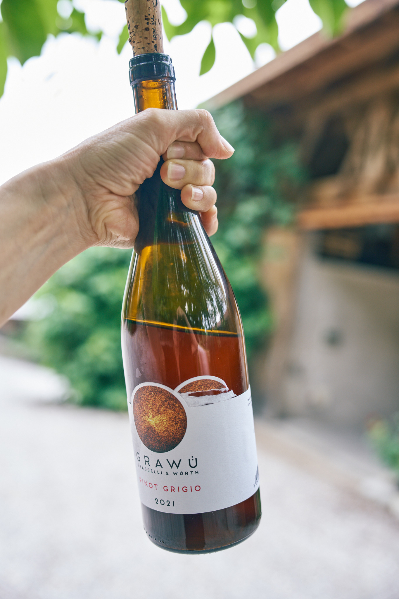 Una mano tiene una bottiglia di GRAWÜ Pinot Grigio 2021 alla luce naturale